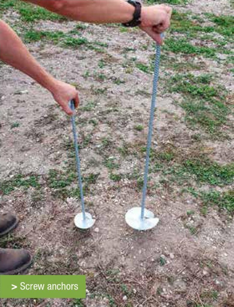 Image of two screw anchors being installed in the ground in a UK vineyard.